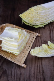 切开的大白菜和一簸箕白菜片放在木桌上