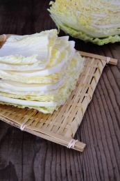 切开的大白菜和一簸箕白菜片放在木桌上