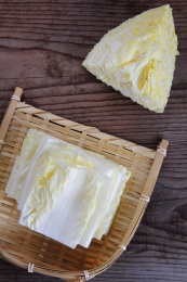 切开的大白菜和一簸箕白菜片放在木桌上