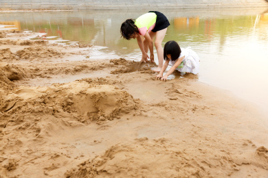 在水边开心玩泥沙的小女孩