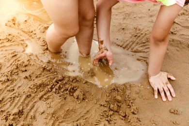 在水边赤脚开心玩泥沙的小女孩