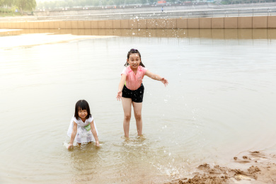 在水边开心玩泥沙的小女孩