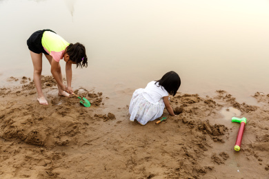 在水边开心玩泥沙的小女孩