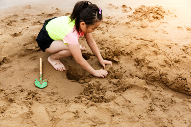 在水边开心玩泥沙的小女孩