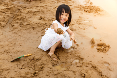 在水边开心玩泥沙的小女孩