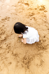在水边开心玩泥沙的小女孩