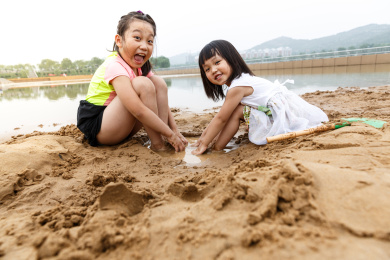 在水边开心玩泥沙的小女孩