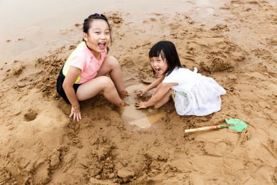 在水边开心玩泥沙的小女孩