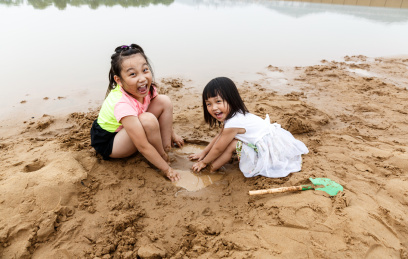 在水边开心玩泥沙的小女孩