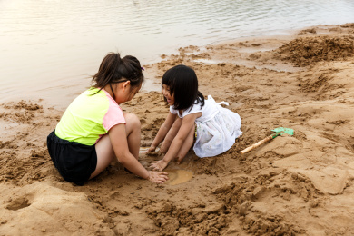 在水边开心玩泥沙的小女孩