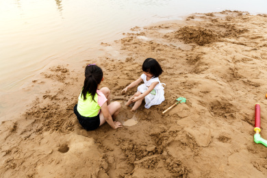 在水边开心玩泥沙的小女孩