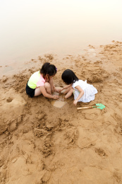 在水边开心玩泥沙的小女孩
