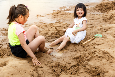 在水边开心玩泥沙的小女孩