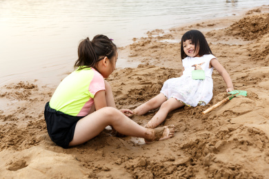 在水边开心玩泥沙的小女孩
