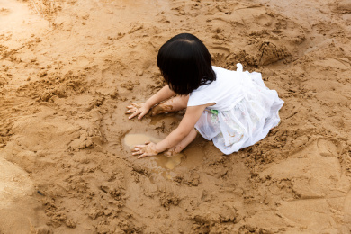 在水边开心玩泥沙的小女孩