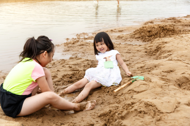 在水边开心玩泥沙的小女孩