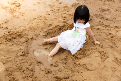 在水边开心玩泥沙的小女孩