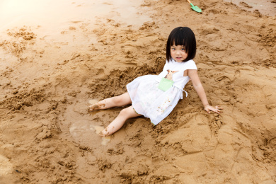 在水边开心玩泥沙的小女孩