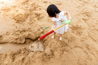 在水边开心玩泥沙的小女孩