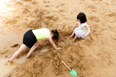 在水边开心玩泥沙的小女孩