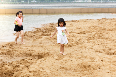 在水边开心玩泥沙的小女孩