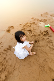 在水边开心玩泥沙的小女孩