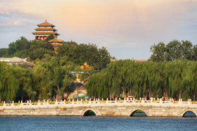 中国北京北海公园蓝色的湖泊和远处的石拱桥及景山公园万春亭远景