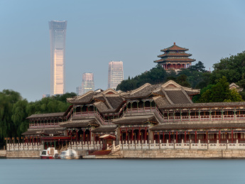 中国北京北海公园蓝色湖面对岸的长廊及远景景山上的万春亭和CBD现代建筑