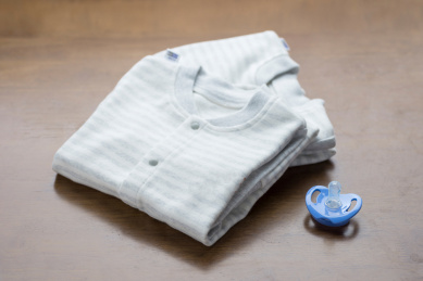 整齐折叠的婴幼儿连体服装和安抚奶嘴