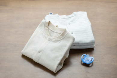 整齐折叠的婴幼儿连体服装和安抚奶嘴