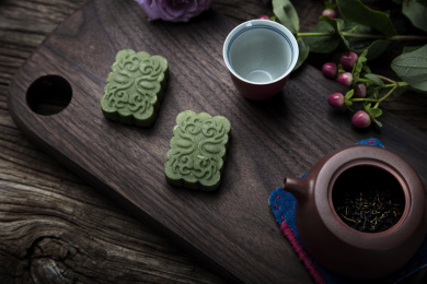 珊瑚红小杯，搭配绿色龙井茶糕，朱红色紫砂小壶里面装着祁红干茶