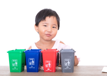 白背景前坐在桌子边的中国小女孩在学习垃圾分类小知识