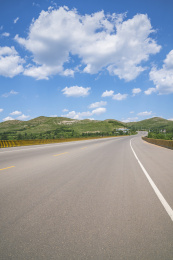 晴朗天气蓝天白云下的山区宽阔的沥青公路