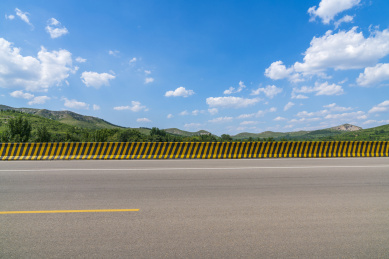 晴朗天气蓝天白云下的山区宽阔的沥青公路
