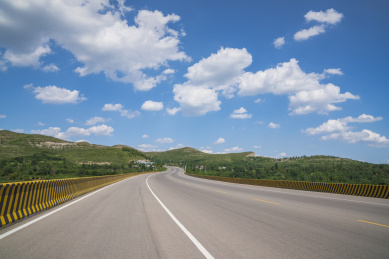 晴朗天气蓝天白云下的山区宽阔的沥青公路