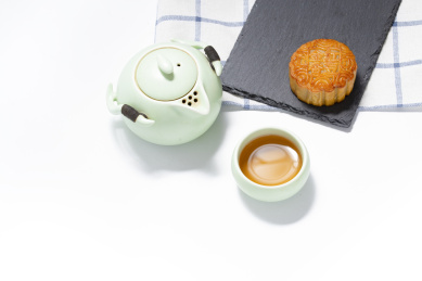 白底上横向摆放的月饼和青瓷茶壶茶杯
