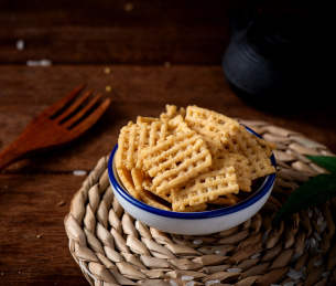 深色背景下蓝色瓷碗里的金黄色锅巴