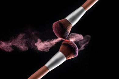化妆刷在黑色背景下相碰，粉底飞扬