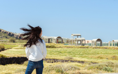 亚裔女性在希腊圣托里尼岛的春天的田园里头发被风吹散