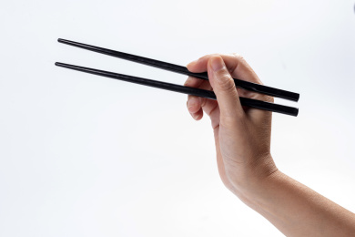 女性手持筷子在白背景前的特写