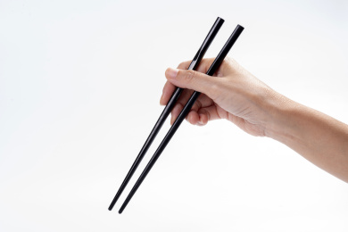 女性手持筷子在白背景前的特写