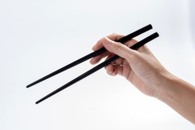 女性手持筷子在白背景前的特写