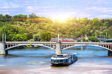 夕阳下的捷克共和国布拉格市伏尔塔瓦河上的桥梁和游船