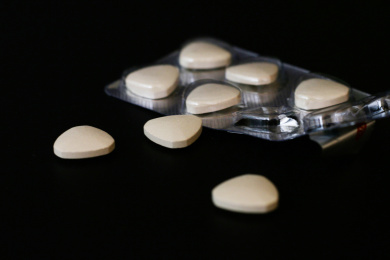 纯黑色卡纸上散落的药片药粒