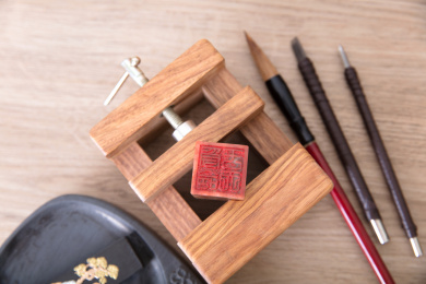 桌子上固定着印章的刻床和砚台及几杆毛笔