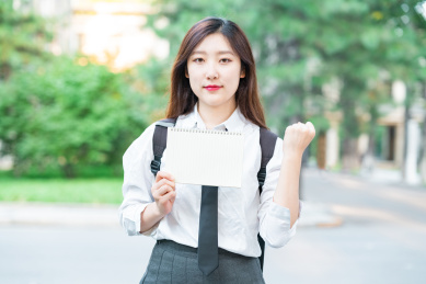 一个美女大学生手拿着手机头戴着耳机学习网络课程互联网课程在线学习教育概念
