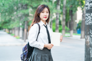 美女大学生背着书包去图书馆拿着书本课本自习学习教育概念