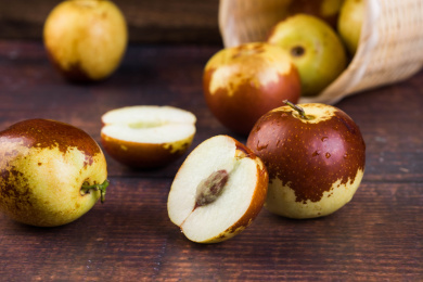 一个装有冬枣的竹筐倒了，把冬枣撒落在木纹桌上