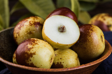 放在木盘里的新鲜水果冬枣，旁边还洒落了一些冬枣