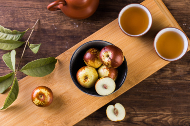 放在黑色碗里的冬枣，旁边还有茶杯